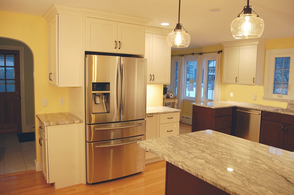Example of a mid-sized transitional u-shaped light wood floor eat-in kitchen design in Boston with an undermount sink, shaker cabinets, white cabinets, quartz countertops, stainless steel appliances and a peninsula