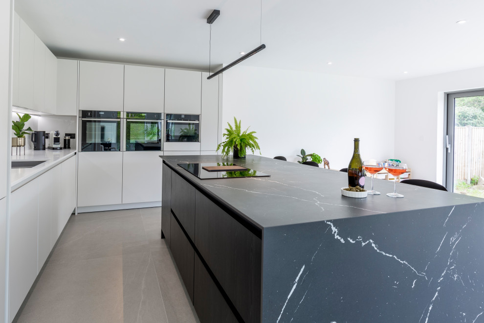 Diseño de cocina lineal y gris y blanca contemporánea grande abierta con salpicadero verde, una isla, suelo gris y encimeras grises