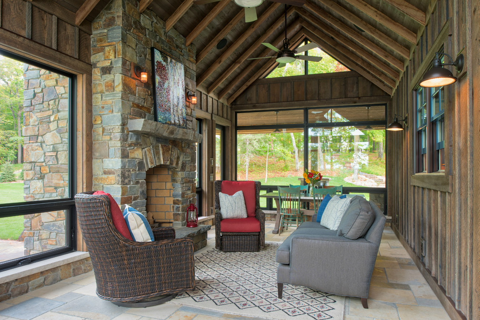 Inspiration for a large country sunroom in Minneapolis with travertine floors, a standard fireplace, a stone fireplace surround, a standard ceiling and beige floor.