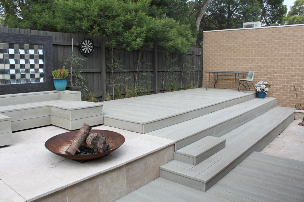 Expansive mediterranean backyard deck in Melbourne with a fire feature.