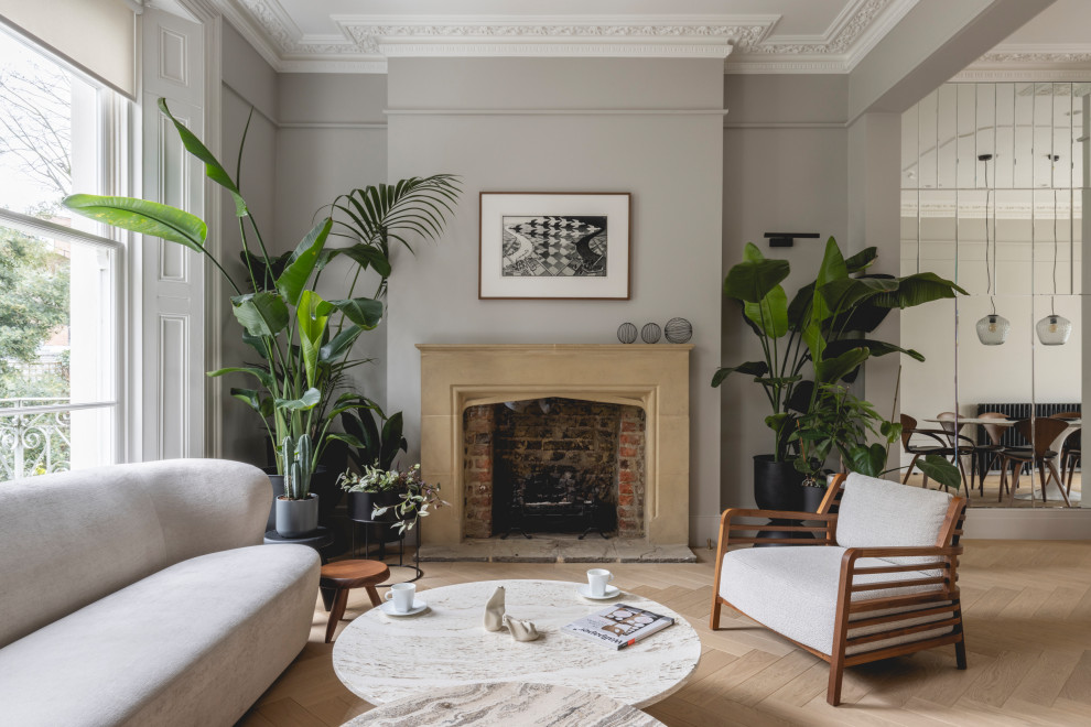 This is an example of a medium sized contemporary formal open plan living room in London with green walls, light hardwood flooring, a standard fireplace, a plastered fireplace surround and beige floors.