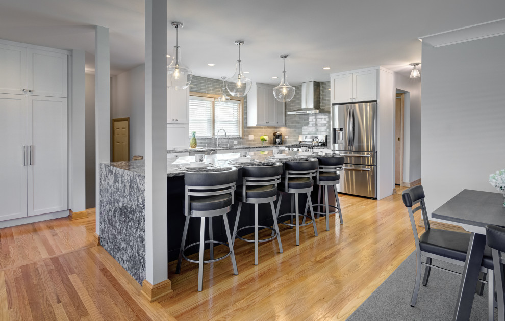Inspiration for a large transitional l-shaped kitchen in Chicago with an undermount sink, shaker cabinets, white cabinets, grey splashback, stainless steel appliances, with island, beige floor and grey benchtop.