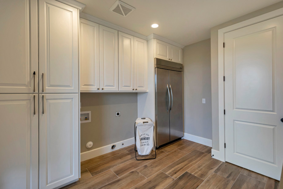 Example of a mid-sized transitional galley porcelain tile and brown floor home design design in Phoenix with a drop-in sink, raised-panel cabinets, white cabinets, quartzite countertops, gray walls and a side-by-side washer/dryer