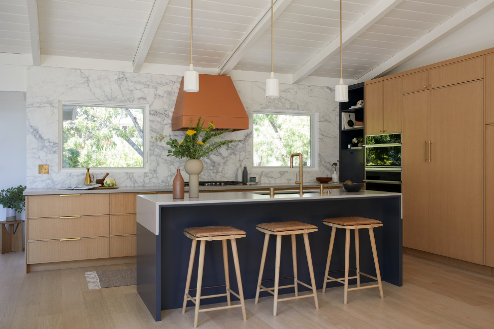 This is an example of a medium sized retro l-shaped open plan kitchen in San Francisco with a submerged sink, shaker cabinets, light wood cabinets, engineered stone countertops, white splashback, marble splashback, integrated appliances, light hardwood flooring, an island, brown floors, grey worktops and exposed beams.