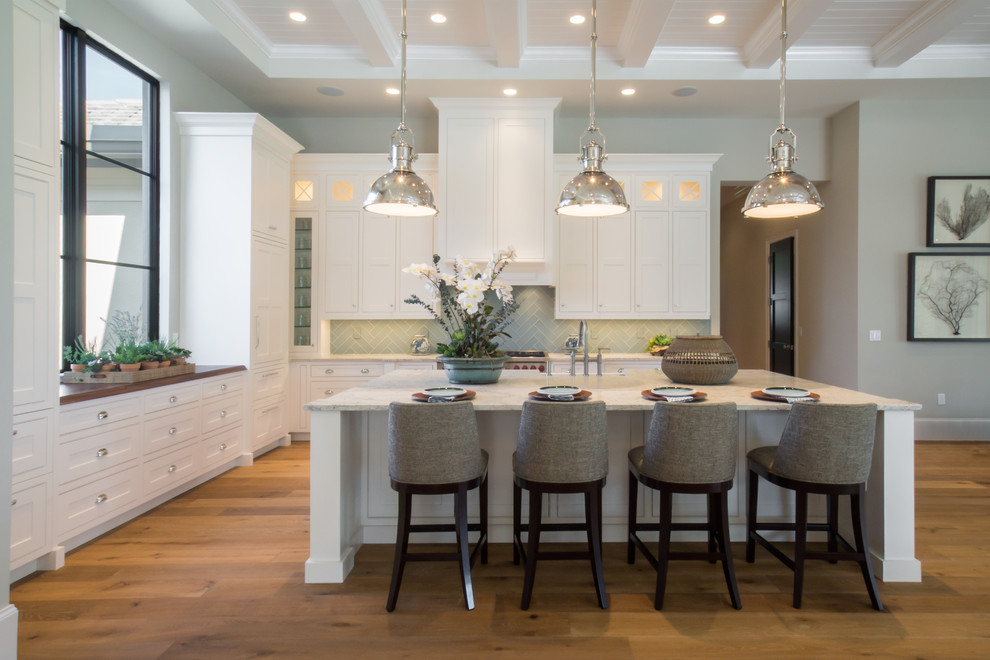 Example of a large transitional l-shaped eat-in kitchen design in Miami with shaker cabinets, white cabinets, granite countertops, green backsplash and an island