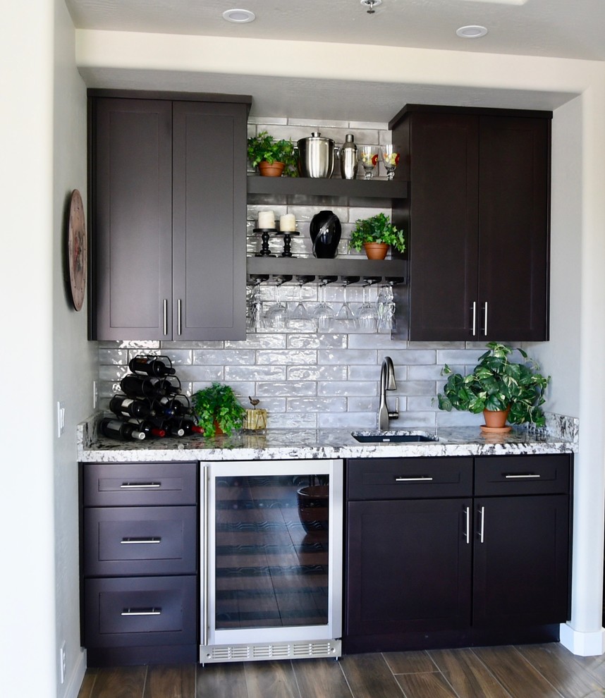 Photo of a small transitional wet bar in Phoenix with an undermount sink, shaker cabinets, dark wood cabinets, granite benchtops, grey splashback, subway tile splashback and multi-coloured benchtop.