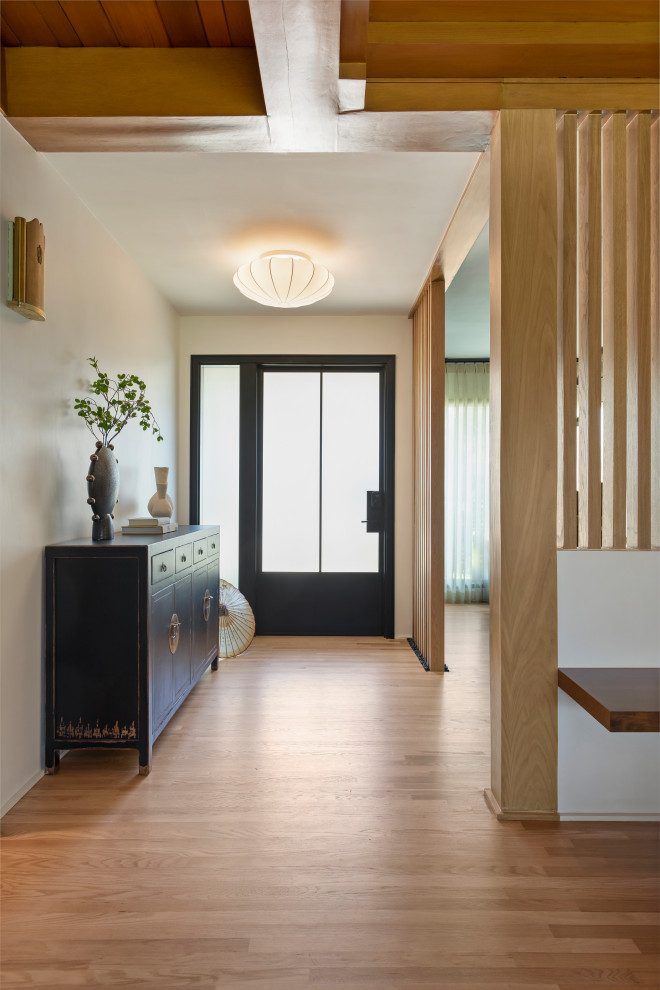 Small contemporary entrance in Los Angeles with white walls, light hardwood flooring, a single front door, a black front door and black floors.
