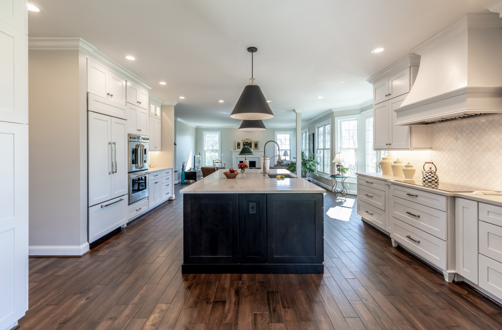 Inspiration for a contemporary kitchen in DC Metro with white cabinets, granite benchtops, white splashback, ceramic splashback, stainless steel appliances, medium hardwood floors, a peninsula, brown floor and white benchtop.