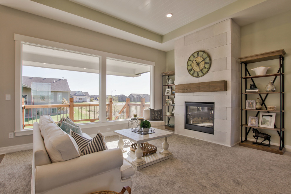 This is an example of a mid-sized country open concept living room in Wichita with green walls, carpet, a standard fireplace, a concrete fireplace surround, a wall-mounted tv and grey floor.