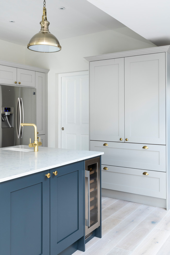 Photo of a large transitional u-shaped eat-in kitchen in London with a double-bowl sink, shaker cabinets, blue cabinets, quartzite benchtops, with island and grey floor.