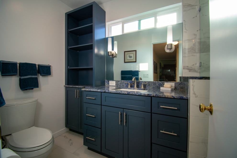 На фото: маленькая ванная комната в стиле неоклассика (современная классика) с фасадами в стиле шейкер, синими фасадами, накладной ванной, душем над ванной, унитазом-моноблоком, белой плиткой, керамогранитной плиткой, белыми стенами, полом из керамогранита, врезной раковиной, столешницей из гранита, белым полом, душем с распашными дверями, синей столешницей, нишей, тумбой под одну раковину и встроенной тумбой для на участке и в саду