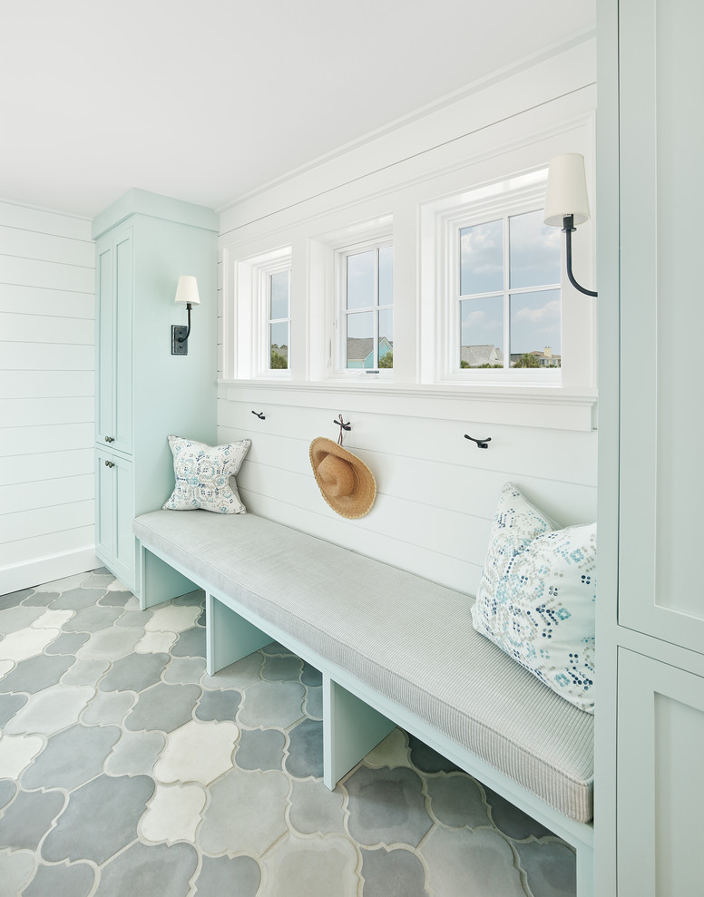 Inspiration for a large beach style galley utility room in Charleston with recessed-panel cabinets, blue cabinets, white walls, concrete floors and grey floor.