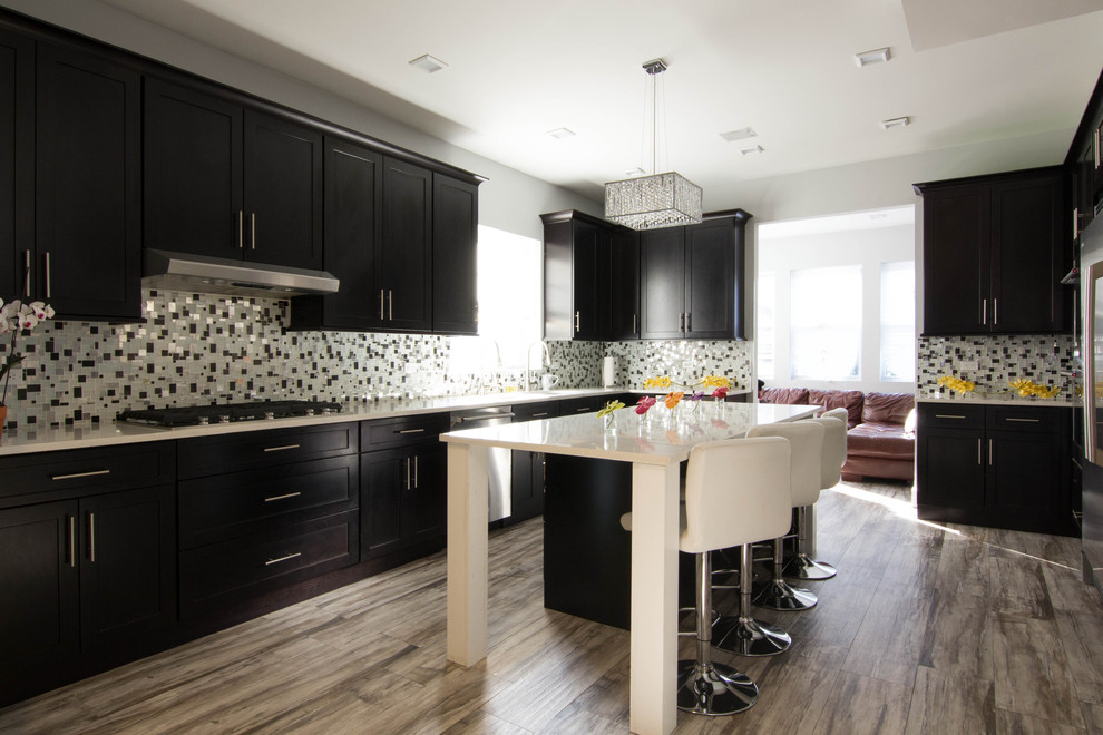 Photo of a large transitional u-shaped eat-in kitchen in New York with an undermount sink, shaker cabinets, dark wood cabinets, quartzite benchtops, multi-coloured splashback, mosaic tile splashback, stainless steel appliances, ceramic floors, with island and brown floor.