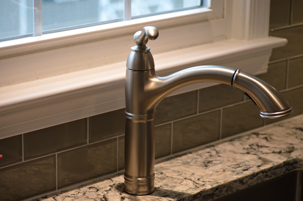 Example of a large transitional u-shaped ceramic tile and gray floor home design design with a farmhouse sink, raised-panel cabinets, white cabinets, quartz countertops, gray backsplash, glass tile backsplash, stainless steel appliances and an island