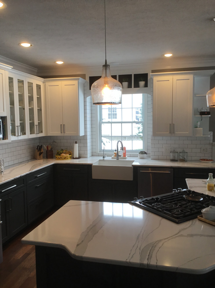 Inspiration for a mid-sized transitional l-shaped dark wood floor and red floor eat-in kitchen remodel with a farmhouse sink, recessed-panel cabinets, gray cabinets, quartz countertops, white backsplash, subway tile backsplash, stainless steel appliances, an island and white countertops