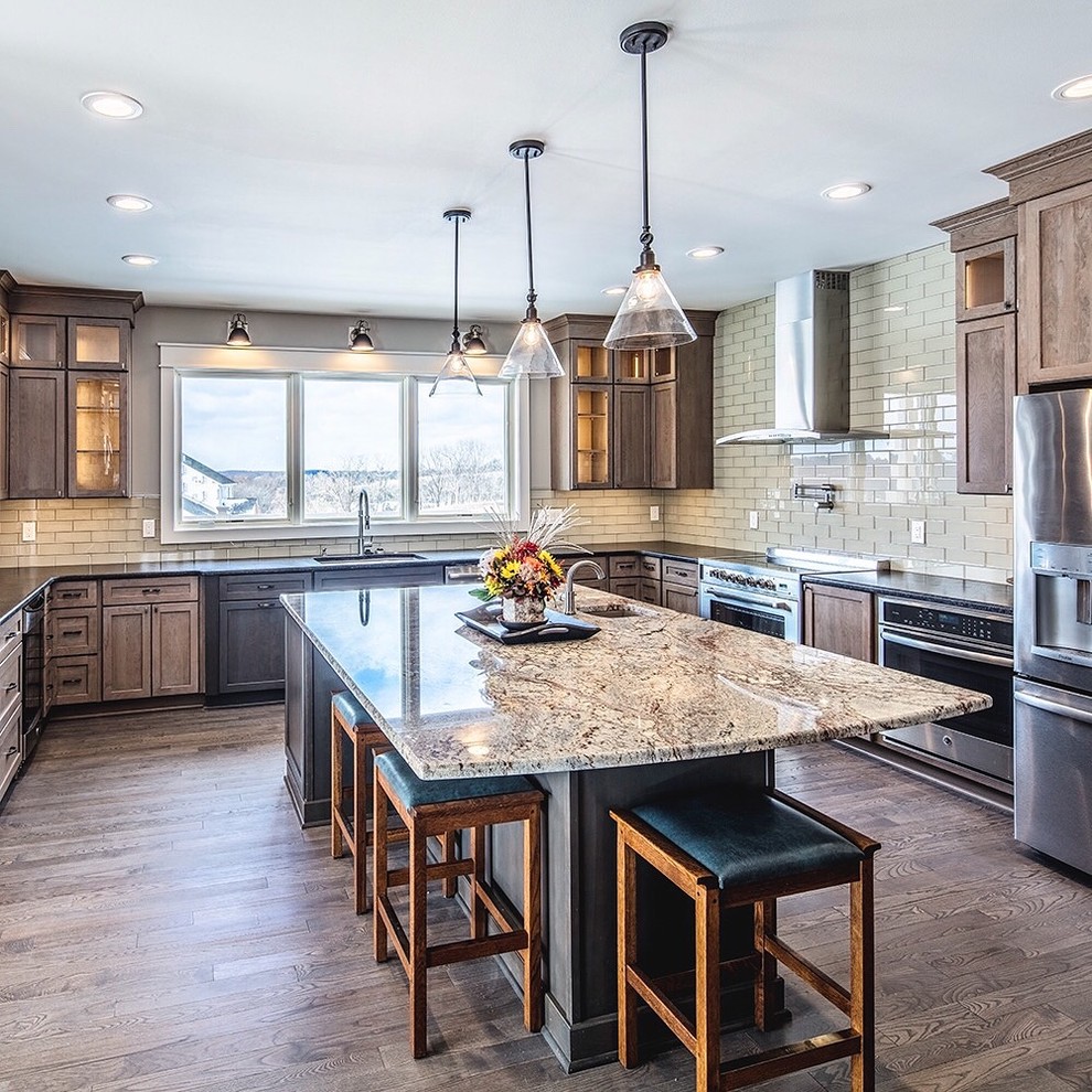 Inspiration for a large transitional u-shaped eat-in kitchen in Other with an undermount sink, shaker cabinets, distressed cabinets, granite benchtops, beige splashback, glass tile splashback, stainless steel appliances, medium hardwood floors, with island and brown floor.