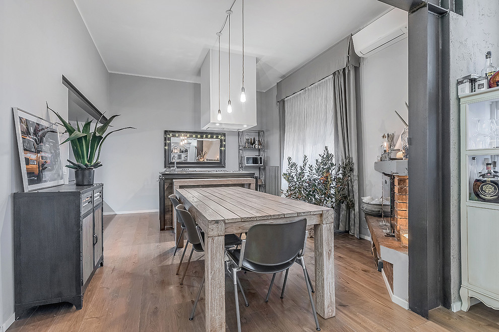 Photo of a scandinavian dining room in Florence with grey walls, light hardwood floors, a corner fireplace and a brick fireplace surround.