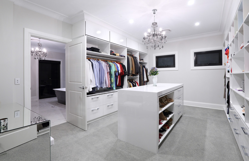 This is an example of an expansive contemporary gender-neutral walk-in wardrobe in Sunshine Coast with flat-panel cabinets, white cabinets, carpet and grey floor.