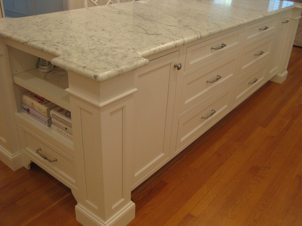 Example of a transitional u-shaped medium tone wood floor eat-in kitchen design in Boston with a farmhouse sink, beaded inset cabinets, white cabinets, marble countertops, white backsplash, subway tile backsplash, stainless steel appliances and an island