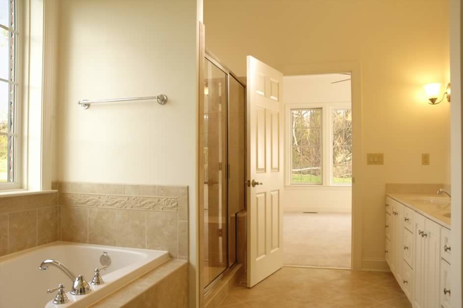 Example of a large transitional master beige tile beige floor drop-in bathtub design in Phoenix with raised-panel cabinets, white cabinets, beige walls, a drop-in sink and a hinged shower door