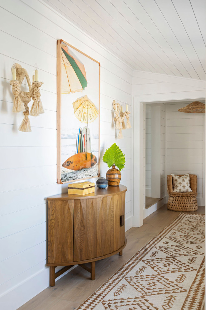 Photo of a beach style hallway in Charleston with white walls, light hardwood floors and planked wall panelling.