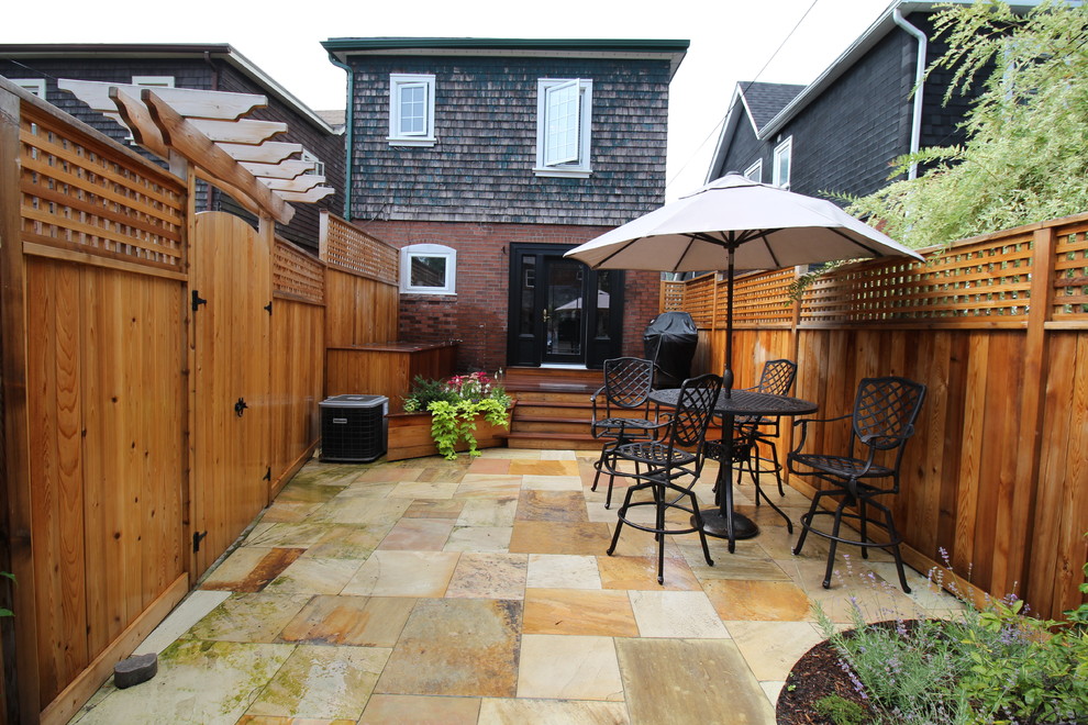 Mid-sized transitional backyard stone patio photo in Toronto with no cover