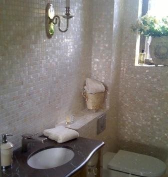 White mother of pearl mosaics in a bathroom area with stone basin