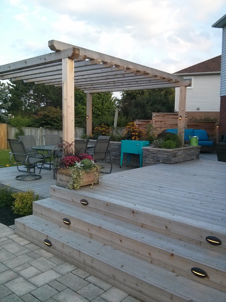 This is an example of an expansive contemporary backyard deck in Toronto with a water feature and a pergola.