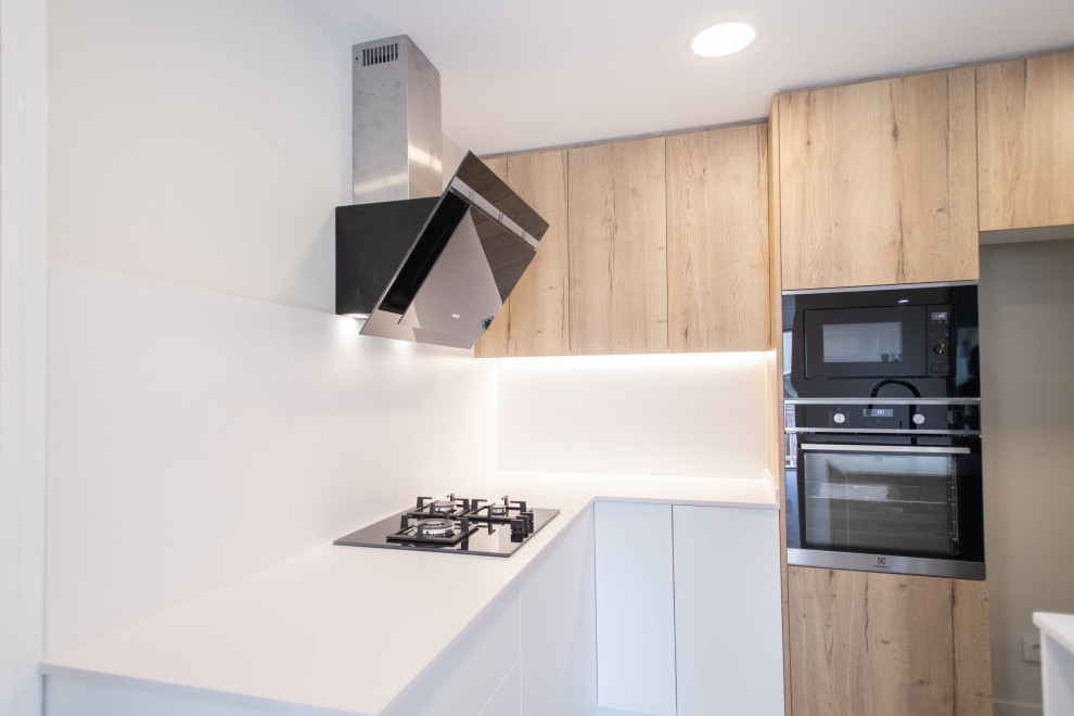 Design ideas for a mid-sized contemporary u-shaped kitchen in Barcelona with a single-bowl sink, flat-panel cabinets, white cabinets, white splashback, black appliances, ceramic floors, no island, beige floor and blue benchtop.