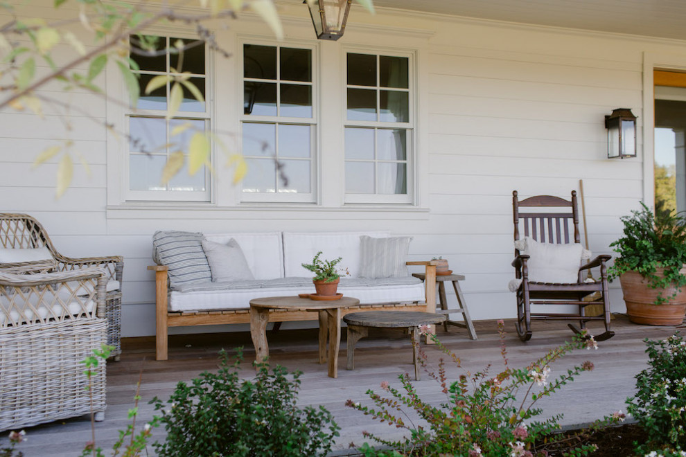 Réalisation d'un grand porche d'entrée de maison avant champêtre avec une terrasse en bois et une extension de toiture.