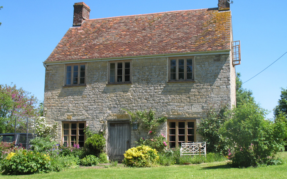 Inspiration for a country two-storey brown house exterior in London with stone veneer, a gable roof and a shingle roof.