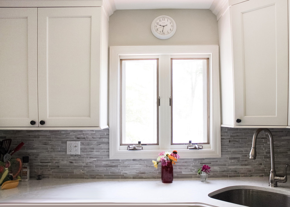 Enclosed kitchen - mid-sized transitional galley light wood floor and brown floor enclosed kitchen idea in New York with an undermount sink, recessed-panel cabinets, white cabinets, marble countertops, beige backsplash, matchstick tile backsplash, stainless steel appliances and no island