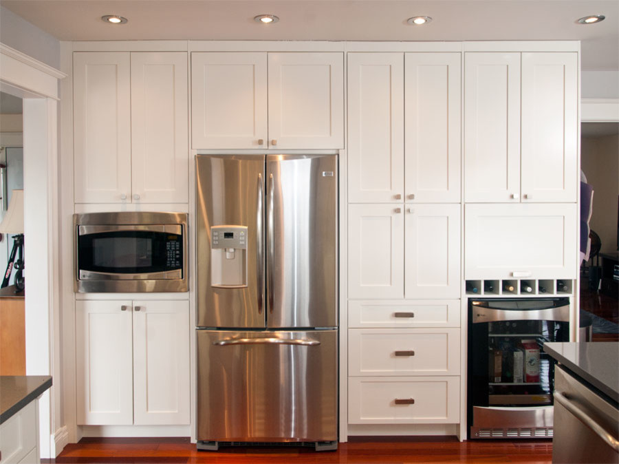 Small transitional u-shaped dark wood floor eat-in kitchen photo with an undermount sink, shaker cabinets, white cabinets, quartzite countertops, gray backsplash, glass tile backsplash, stainless steel appliances and a peninsula