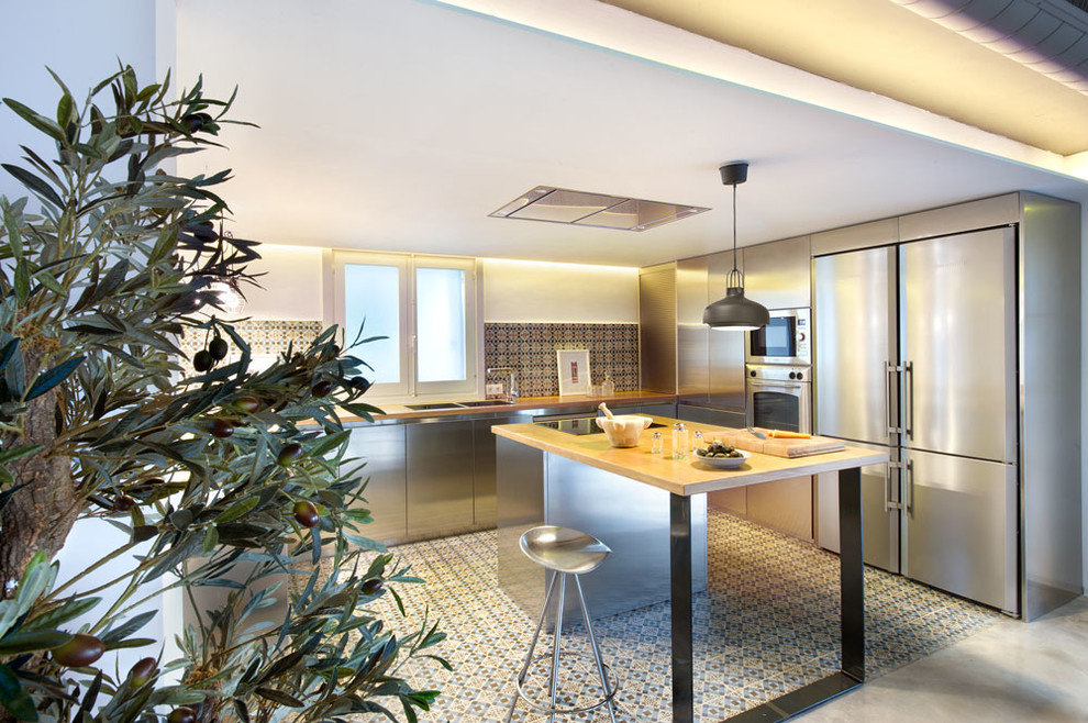 Large contemporary u-shaped eat-in kitchen in Madrid with an undermount sink, flat-panel cabinets, stainless steel cabinets, wood benchtops, multi-coloured splashback, ceramic splashback, stainless steel appliances, ceramic floors and with island.