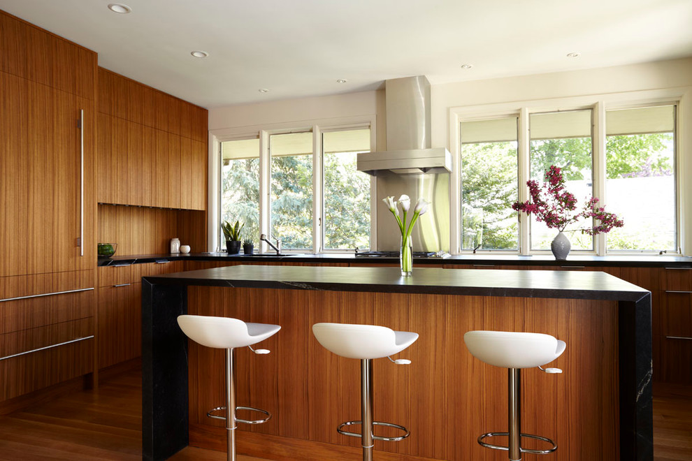 Photo of a modern kitchen in Minneapolis with flat-panel cabinets, medium wood cabinets, metallic splashback, metal splashback and panelled appliances.