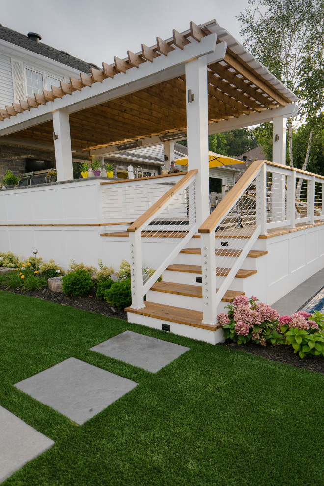Design ideas for a large traditional backyard and ground level deck in Toronto with a pergola and cable railing.