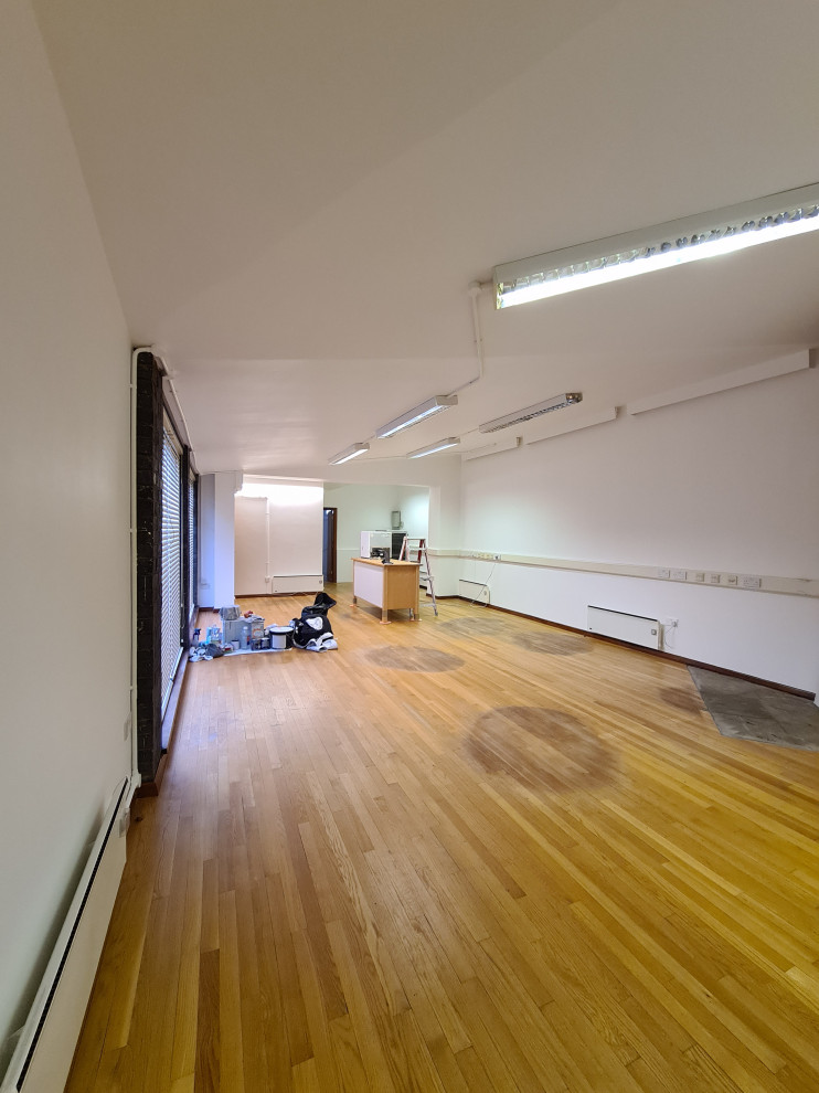 Diseño de sala de manualidades minimalista grande con paredes blancas, suelo de madera oscura, suelo marrón y bandeja