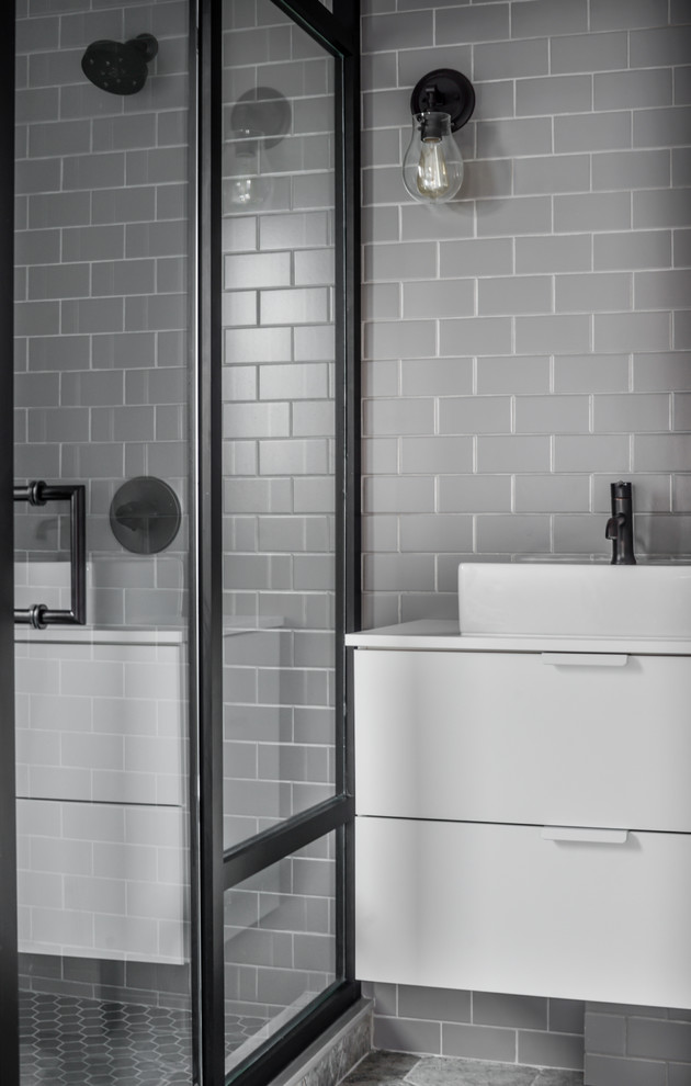 Photo of a mid-sized contemporary bathroom in Toronto with flat-panel cabinets, white cabinets, a corner shower, gray tile, subway tile, grey walls, ceramic floors, a vessel sink, solid surface benchtops and a hinged shower door.