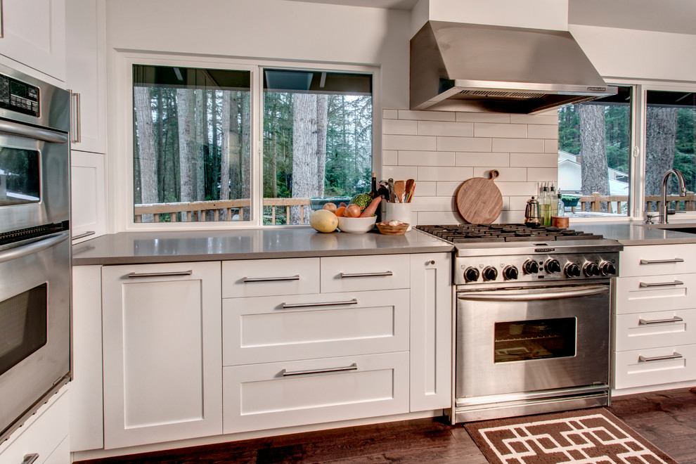 Transitional l-shaped medium tone wood floor open concept kitchen photo in Seattle with an undermount sink, shaker cabinets, white cabinets, quartz countertops, white backsplash, subway tile backsplash, stainless steel appliances and an island