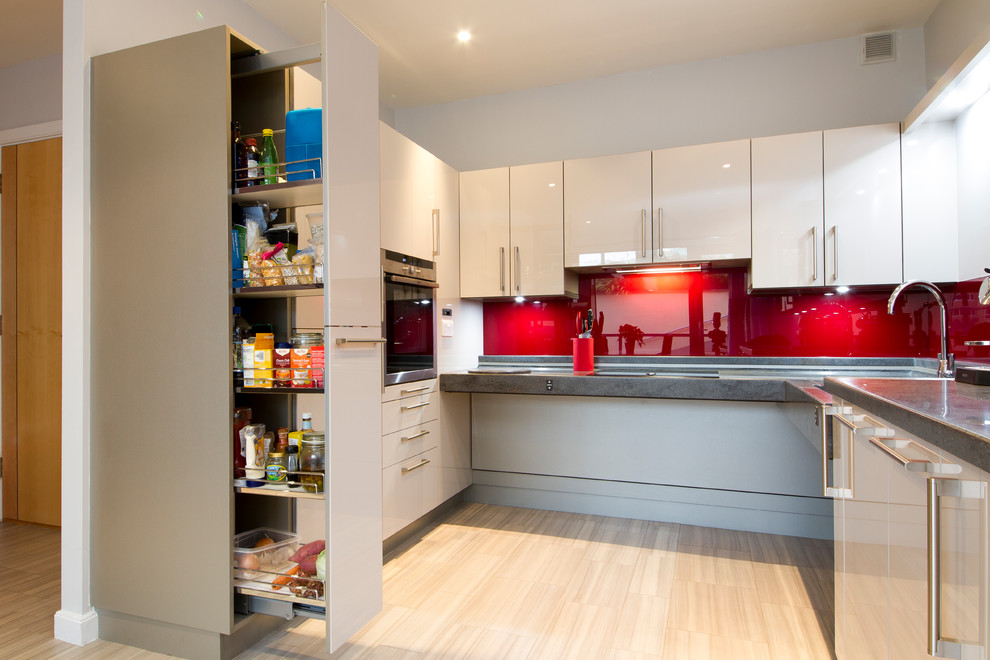 Design ideas for a small contemporary u-shaped open plan kitchen in Buckinghamshire with an integrated sink, flat-panel cabinets, white cabinets, solid surface benchtops, red splashback, glass sheet splashback, stainless steel appliances, laminate floors, no island and beige floor.