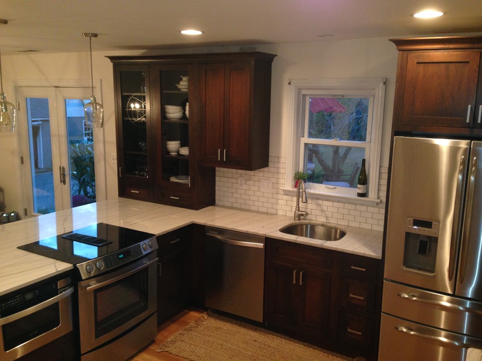 Example of a small transitional u-shaped light wood floor home design design in Baltimore with a single-bowl sink, glass-front cabinets, dark wood cabinets, soapstone countertops, white backsplash, ceramic backsplash, stainless steel appliances and a peninsula