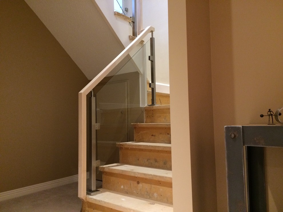 Inspiration for a contemporary wood u-shaped staircase in Toronto with wood risers and glass railing.
