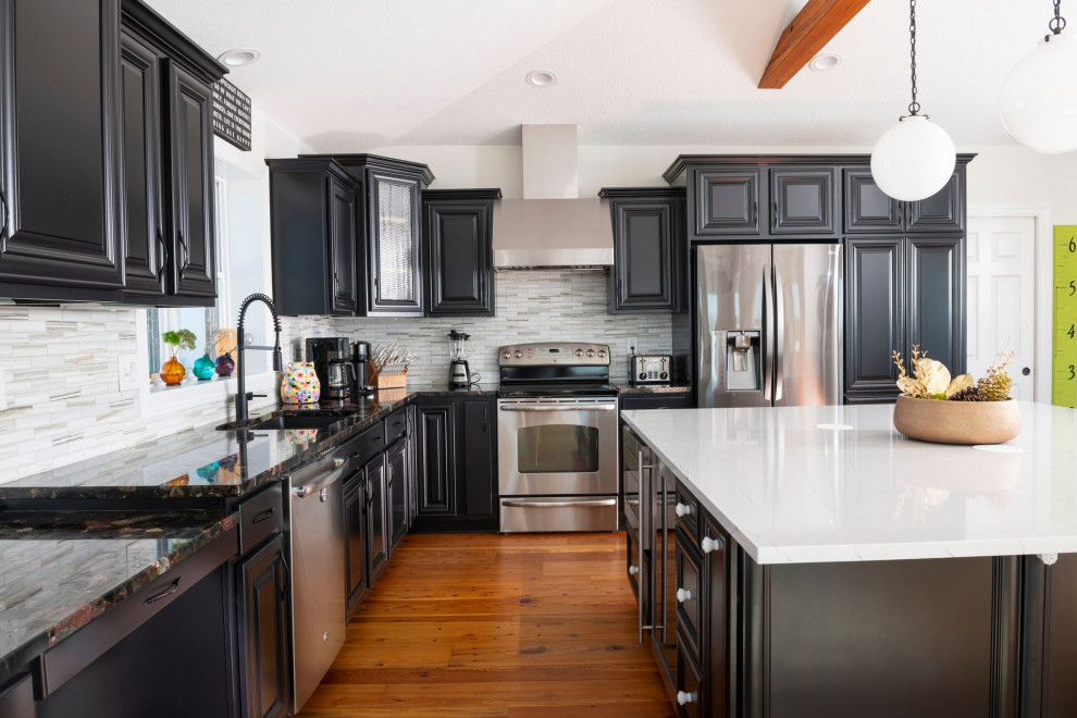 This is an example of a large country open plan kitchen in Cedar Rapids with black cabinets, grey splashback, ceramic splashback, stainless steel appliances, dark hardwood floors, with island, red floor and white benchtop.