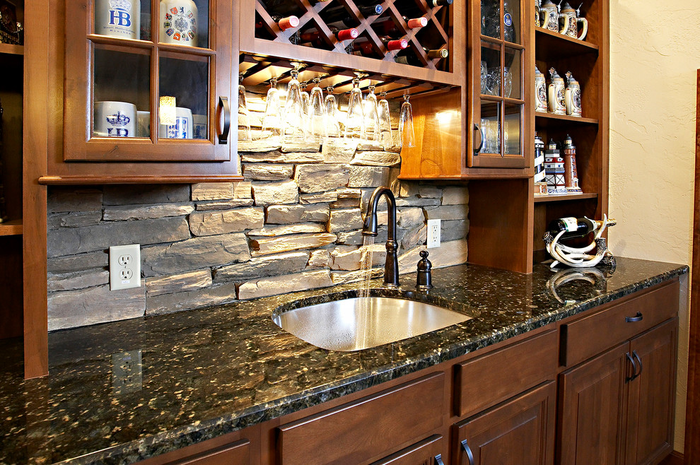 Design ideas for a large country seated home bar in St Louis with an undermount sink, open cabinets, medium wood cabinets, granite benchtops, multi-coloured splashback, stone tile splashback and medium hardwood floors.