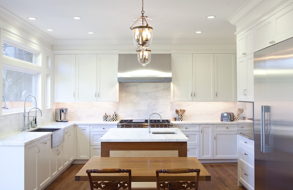 Traditional u-shaped separate kitchen in San Francisco with shaker cabinets, stainless steel appliances, a farmhouse sink, white cabinets, marble benchtops, white splashback and stone slab splashback.