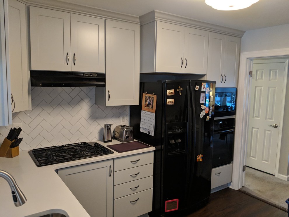 Inspiration for a mid-sized country l-shaped kitchen pantry in Baltimore with shaker cabinets, grey cabinets, quartz benchtops, white splashback, ceramic splashback, black appliances, no island and white benchtop.