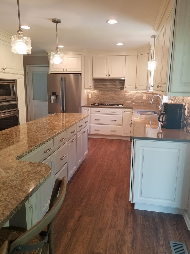 Open concept kitchen - large transitional l-shaped dark wood floor open concept kitchen idea with an undermount sink, raised-panel cabinets, white cabinets, granite countertops, metallic backsplash, matchstick tile backsplash, stainless steel appliances and an island