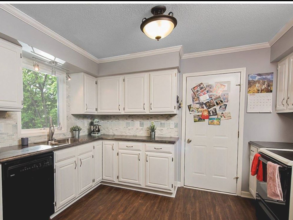 Mid-sized transitional u-shaped dark wood floor and brown floor open concept kitchen photo with a double-bowl sink, raised-panel cabinets, white cabinets, laminate countertops, gray backsplash, ceramic backsplash, black appliances and an island