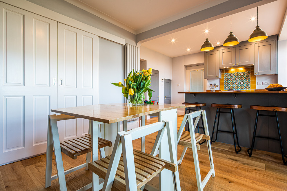 Mid-sized eclectic u-shaped eat-in kitchen in Other with an undermount sink, shaker cabinets, grey cabinets, wood benchtops, yellow splashback, terra-cotta splashback, a peninsula, brown floor and brown benchtop.