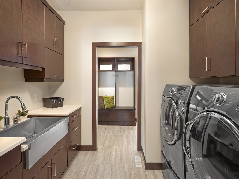 Inspiration for a contemporary galley laundry room in Calgary with a farmhouse sink, flat-panel cabinets, dark wood cabinets, beige walls, a side-by-side washer and dryer, grey floor and beige benchtop.
